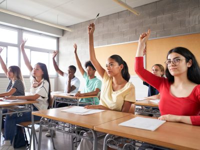 Multi-ethnic students in class with hands raised Multi-ethnic students in class with hands raised